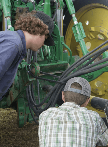 Two boys inspecting farm machinery